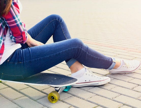 Young female sat on skateboard watching